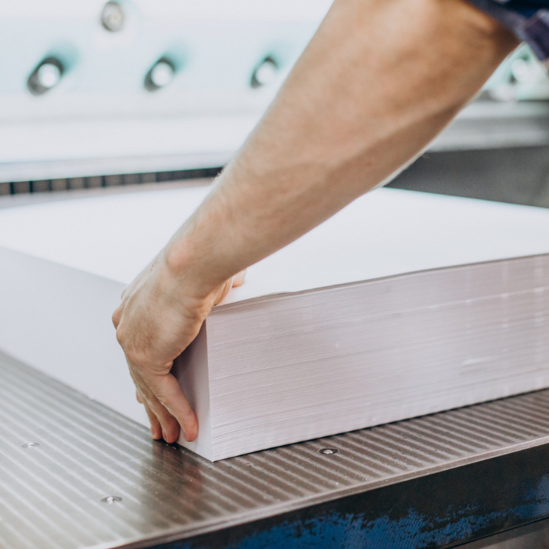 Stack of freshly printed sheets being squared up before finishing
